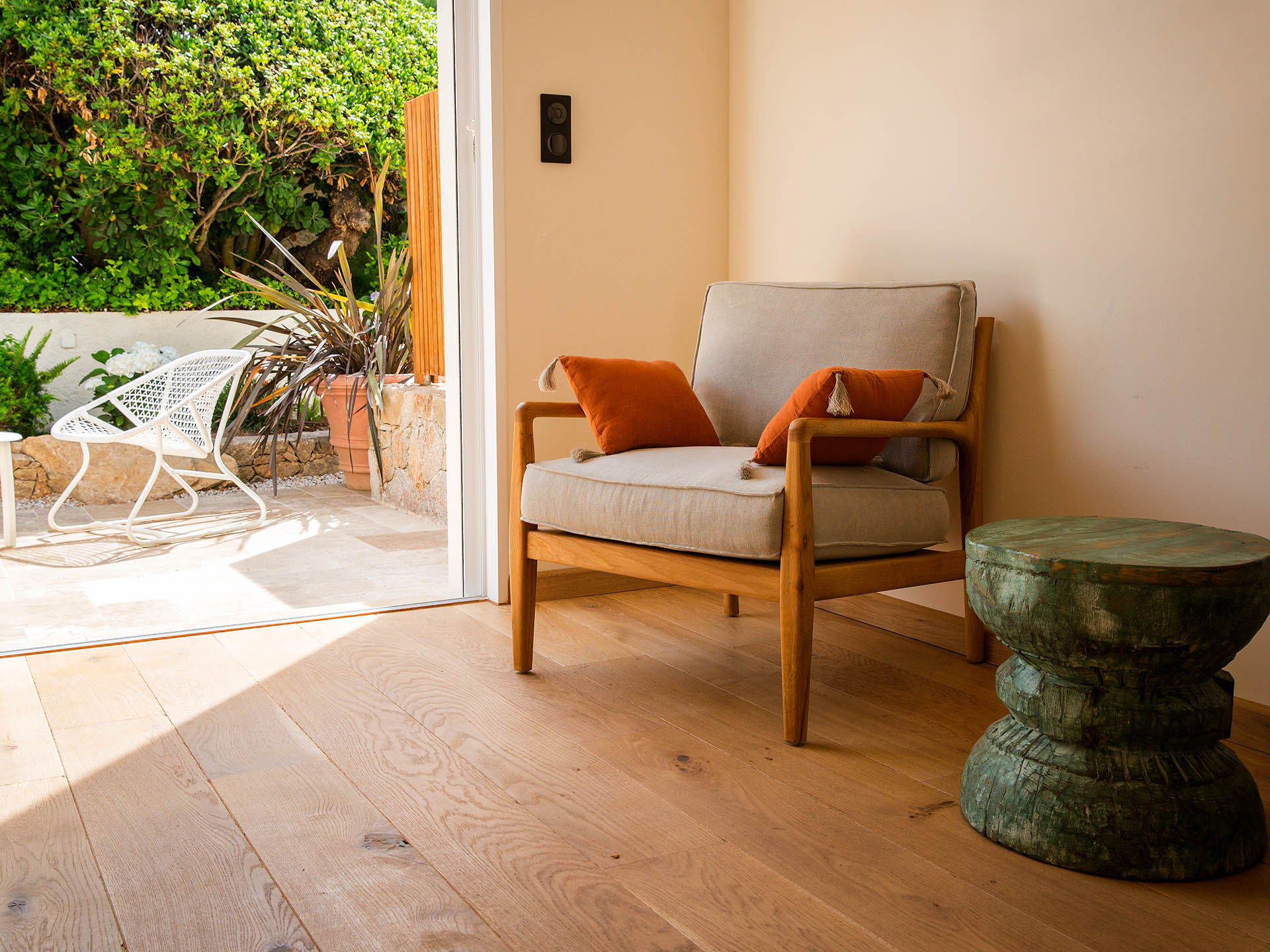 Espace intérieur-extérieur d’hôtel avec fauteuil en bois, terrasse végétalisée et ambiance méditerranéenne