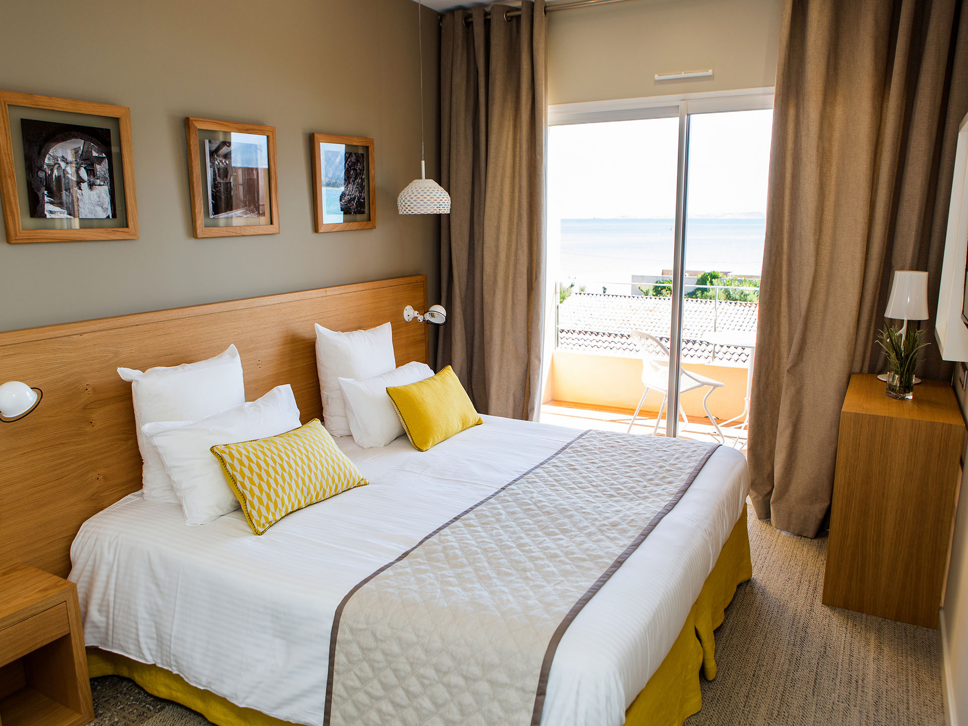Chambre d’hôtel moderne avec lit double et balcon offrant une vue sur la mer