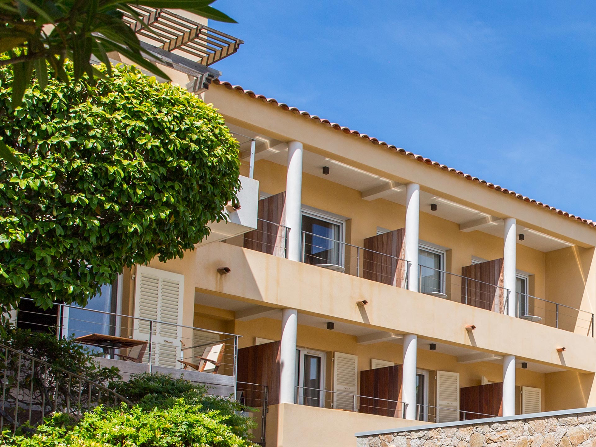 Façade de l’hôtel de style méditerranéen avec balcons et végétation