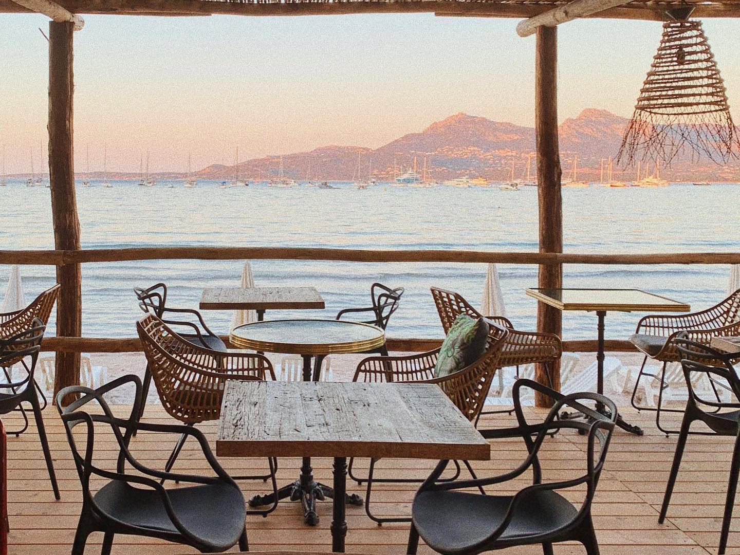 Terrasse de Marco Plage avec tables en bois et vue sur la baie de Calvi