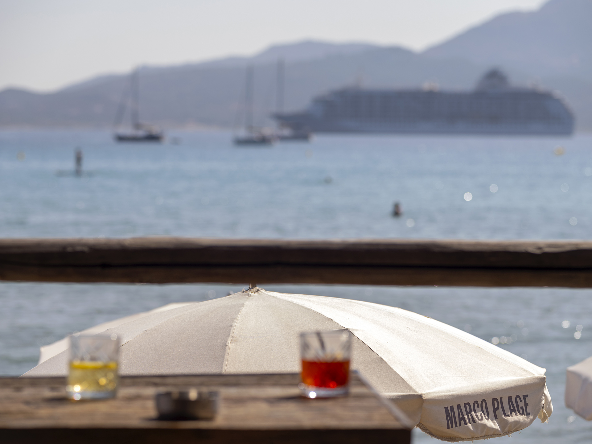 Table de Marco Plage avec boissons sous parasol face à la baie de Calvi